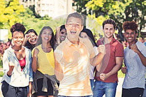 Young male student with group of cheering young adults