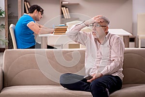 Young male student and his grandfather at home