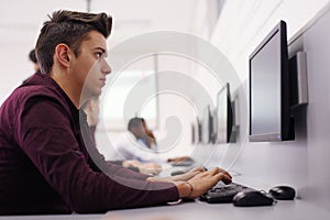 Young male student learning and working at  comp lab class. Young caucasian  student resolving his problem about computer lab test