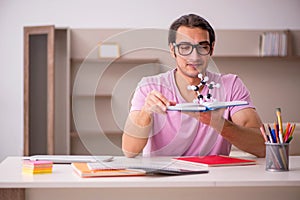 Young male student physicist preparing for exam at home