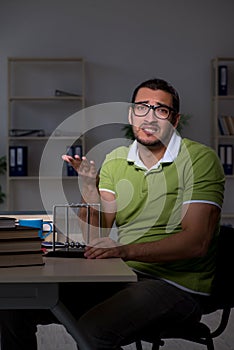 Young male student physicist working hard at night time