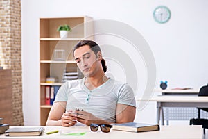 Young male student playing cards during exam preparation in the