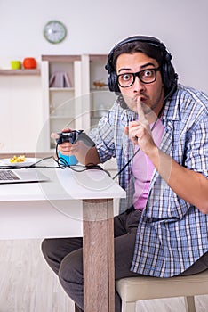 Young male student playing computer games at home