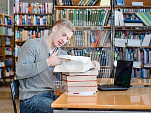 Young male student reading book in library