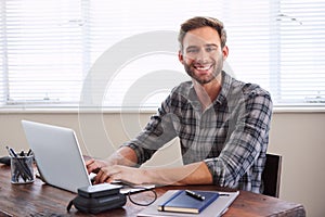 Young male student smiling at camera while working on assignment