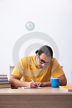 Young male student taking notes during exam preparation