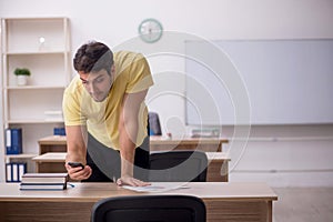 Young male student teacher sitting in the classroom