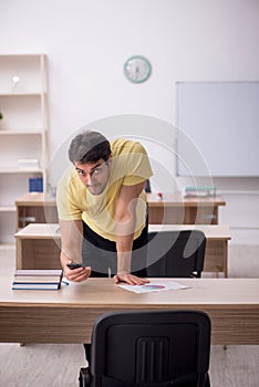 Young male student teacher sitting in the classroom