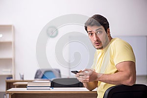 Young male student teacher sitting in the classroom