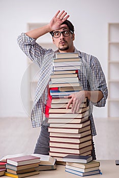 Young male student and too many books in the classroom