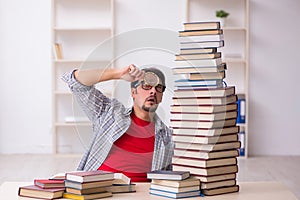 Young male student and too many books in the classroom