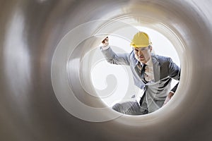 Young male supervisor examining large pipe at construction site