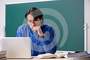 The young male teacher in front of chalkboard