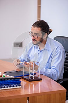 Young male teacher physicist in the classroom