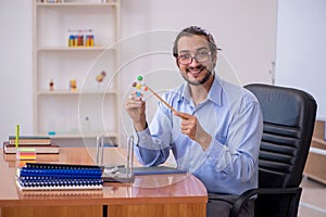 Young male teacher physicist in the classroom