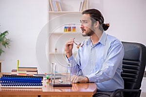 Young male teacher physicist in the classroom