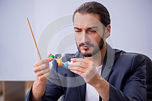 Young male teacher physicist in the classroom