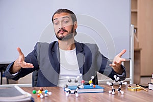 Young male teacher physicist in the classroom