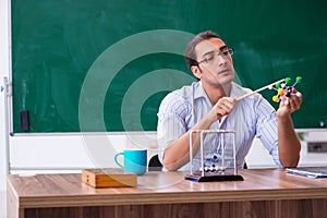 Young male teacher physicist in front of blackboard