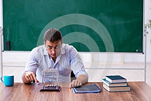 Young male teacher physicist in front of blackboard