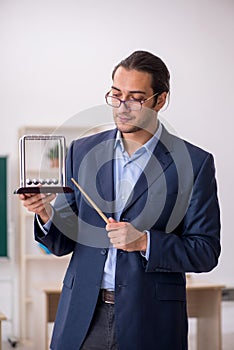 Young male teacher physicist in front of green board