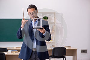 Young male teacher physicist in front of green board