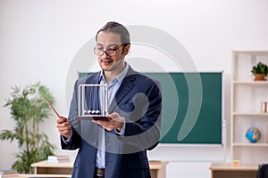 Young male teacher physicist in front of green board