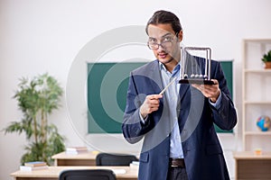 Young male teacher physicist in front of green board