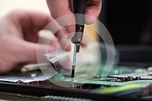 Young male tech or engineer repairs electronic equipment in research facility. A man disassembles a computer with a