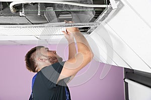 Young male technician checking air conditioner