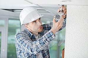 Young male technician installing camera on wall