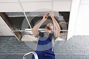 Young male technician repairing air conditioner