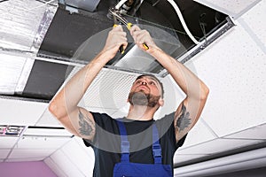 Young male technician repairing air conditioner