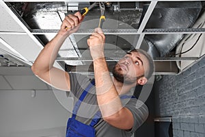 Young male technician repairing air conditioner