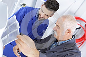 young male technician repairing air conditioner with manager