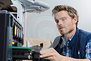 Young male technician repairing printer at office