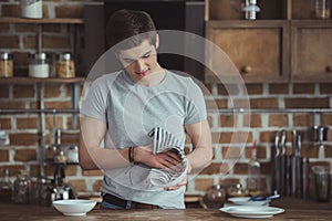 young male teenager cleaning dinnerware with towel