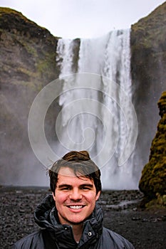 Young male tourist aged 20-25 poses in front of skogafoss waterf