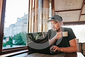 A young male tourist blogger freelancer working on a laptop in a cafe in Istanbul. A view from the window to the world