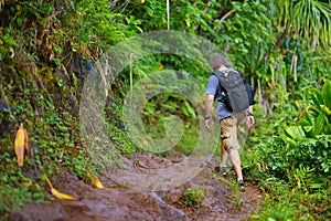 Young male tourist hiking on the famous Kalalau trail along Na Pali coast of the island of Kauai