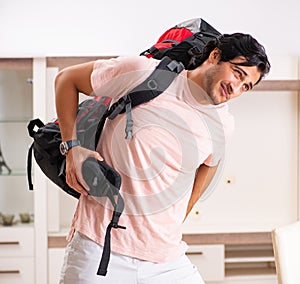 Young male tourist preparing for trip at home