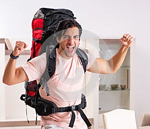 Young male tourist preparing for trip at home