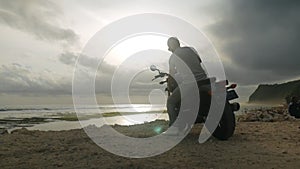 Young male tourist riding to the beach on a motorcycle