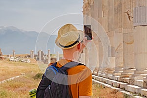Young male tourist taking picture of old antic ruins