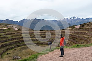 Young male tourist traveling alone in Sacred valley. Solo man hiker with backpack sightseeing inca ruins in Cusco region, Peru