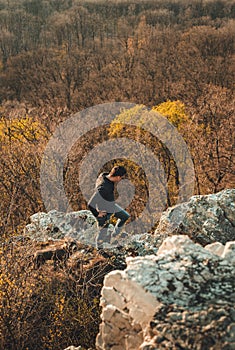 Young male tourist walking on the rocks with perfect view on valley and trees. Man adventurer standing on the rocks over the