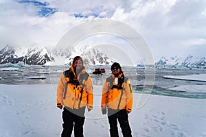 Young Male Tourist with yellow jacket in Antarctica smiling. Icebergs in background. Hiking with backpack in mountains