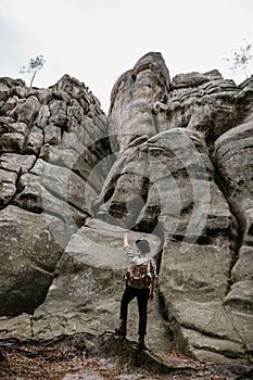 Young male traveler looks at a high rock, an obstacle in the way