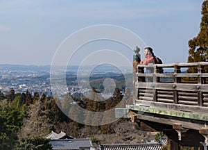 Young male traveller looking at city and landscape while travelling wearing winter red jacket.