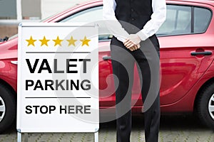 Young Male Valet Standing Near Valet Parking Sign